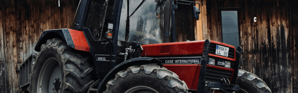 CASE International 1056XL tractor parked in front of a weathered wooden barn wall.